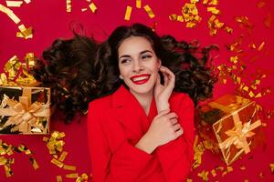 attractive woman celebrating Christmas on red background in confetti photo