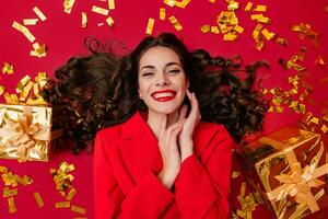 attractive woman celebrating Christmas on red background in confetti photo