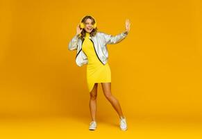 sonriente atractivo mujer escuchando a música en auriculares en amarillo antecedentes foto