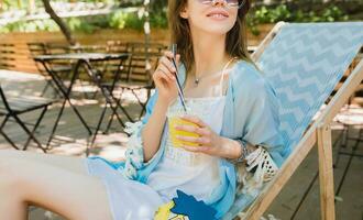 young attractive woman sitting in deck chair in summer fashion outfit photo