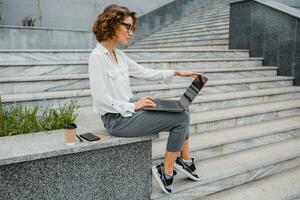 attractive business woman working outside on laptop photo