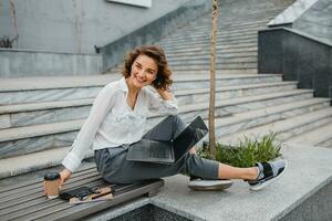 attractive business woman working outside on laptop photo