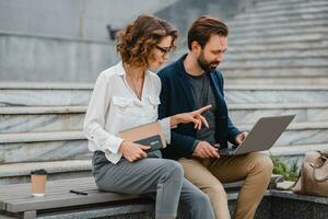 man and woman business partners working together in park photo