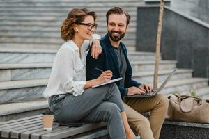 man and woman business partners working together in park photo