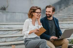 man and woman business partners working together in park photo