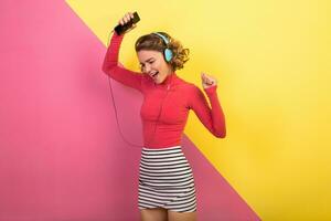 smiling attractive smiling excited woman in stylish colorful outfit dancing and listening to music photo