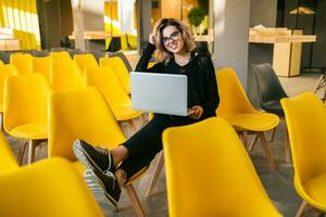 portrait of young attractive woman sitting in lecture hall working on laptop photo