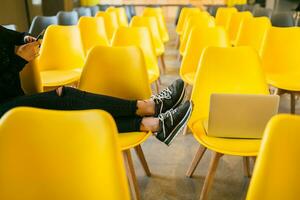close up legs of young stylish woman sitting in lecture hall with laptop photo
