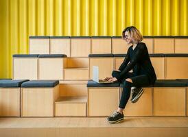 portrait of young attractive woman sitting in lecture hall working on laptop photo