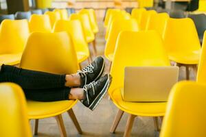 close up legs of young stylish woman sitting in lecture hall with laptop photo