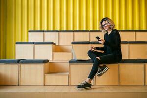 portrait of young attractive woman sitting in lecture hall working on laptop photo