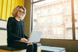 portrait of young attractive woman sitting in lecture hall working on laptop photo