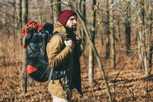 young hipster man traveling with backpack in spring autumn forest photo
