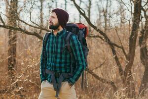 young hipster man traveling with backpack in spring autumn forest photo