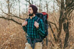 young hipster man traveling with backpack in spring autumn forest photo