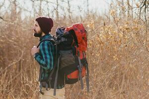 young hipster man traveling with backpack in spring autumn forest photo