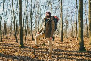 young hipster man traveling with backpack in spring autumn forest photo