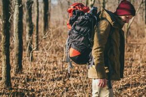 young hipster man traveling with backpack in spring autumn forest photo