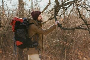 young hipster man traveling with backpack in spring autumn forest photo