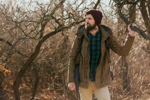 young hipster man traveling with backpack in spring autumn forest photo