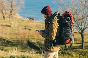 young hipster man traveling with backpack in cold season photo