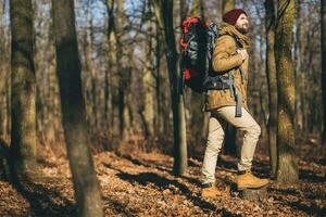 young hipster man traveling with backpack in spring autumn forest photo