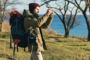 young hipster man traveling with backpack in cold season photo