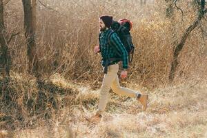 joven hipster hombre de viaje con mochila en primavera otoño bosque foto