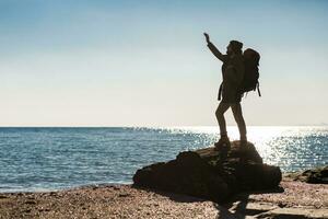 young hipster man traveling with backpack in cold season by the sea photo