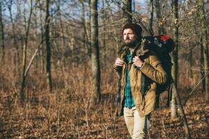 young hipster man traveling with backpack in spring autumn forest photo