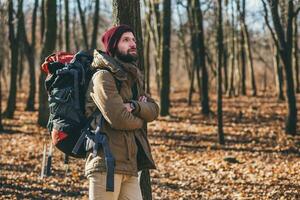 young hipster man traveling with backpack in spring autumn forest photo