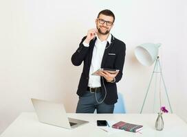 young handsome stylish hipster man in black jacket working at office table, business style photo