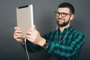 young handsome hipster bearded man on grey background, green checkered shirt photo