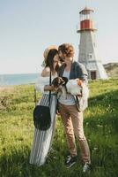 young stylish hipster couple in love walking with dog in countryside, having fun photo