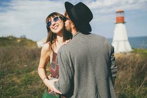 young hipster couple indie style in love walking in countryside, lighthouse on background photo