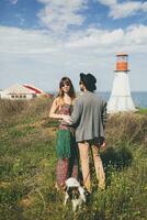 young stylish hipster couple in love walking with dog in countryside photo