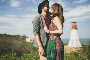 abrazando joven hipster Pareja indie estilo en amor caminando en campo, faro en antecedentes foto