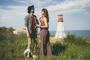 young stylish hipster couple in love walking with dog in countryside photo