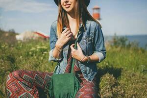 joven mujer en naturaleza, faro mezclilla chaqueta, negro sombrero, verano, elegante accesorios foto