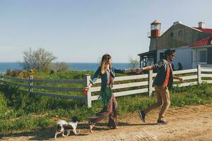 young stylish hipster couple in love walking with dog in countryside, having fun photo