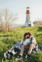 joven elegante hipster Pareja en amor caminando con perro en campo, teniendo divertido foto