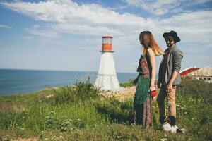 view from back on young stylish hipster couple in love walking with dog in countryside photo