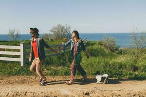 young stylish hipster couple in love walking with dog in countryside photo