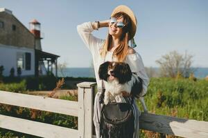 young stylish woman in countryside, holding a dog photo