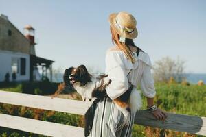 young stylish woman in countryside, holding a dog photo