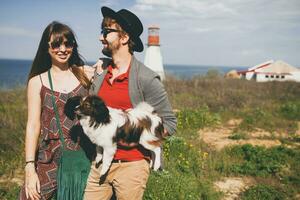 young stylish hipster couple in love walking with dog in countryside photo