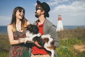 young stylish hipster couple in love walking with dog in countryside photo