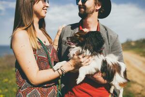 young stylish hipster couple in love walking with dog in countryside photo