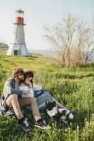 sitting in grass young stylish hipster couple in love walking with dog in countryside photo