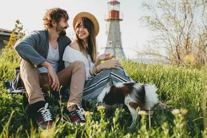 sitting in grass young stylish hipster couple in love walking with dog in countryside photo